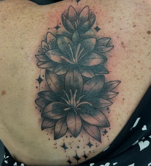 The finished lilies cover-up tattoo on the same client’s back, by Tabitha
