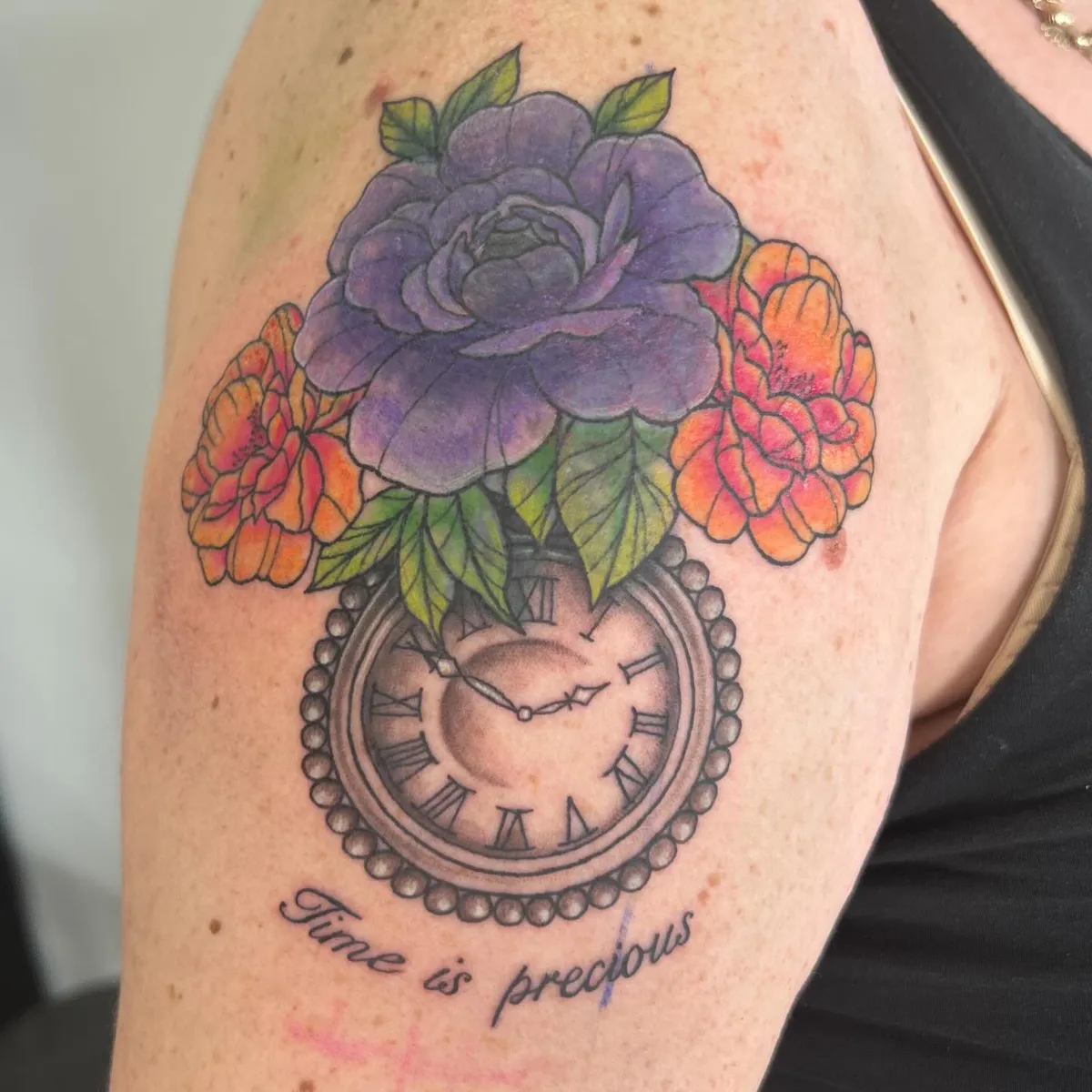 The same shoulder after Tabitha’s cover-up: a purple rose, orange blooms and a pocket watch